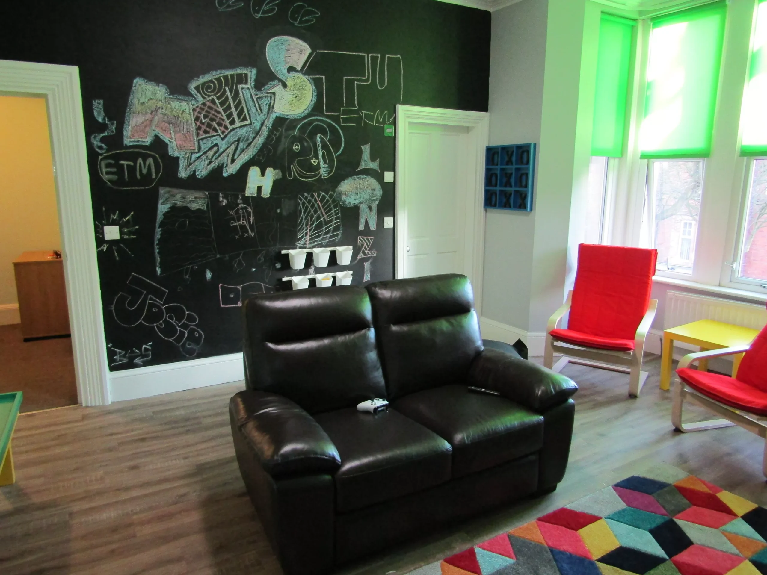 Full length chalkboard with young people's artwork covering the wall in Warwick House