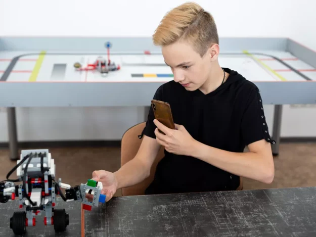 Young person building a robot and taking a photo